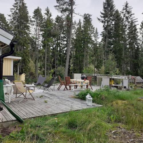a wooden deck with chairs and a table and a grill at Stunning6B2B views,jacuzzi,sauna in Sättra