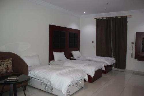 ein Schlafzimmer mit zwei Betten und einem Sofa darin in der Unterkunft جوان سويت للشقق المخدومة in Dschidda