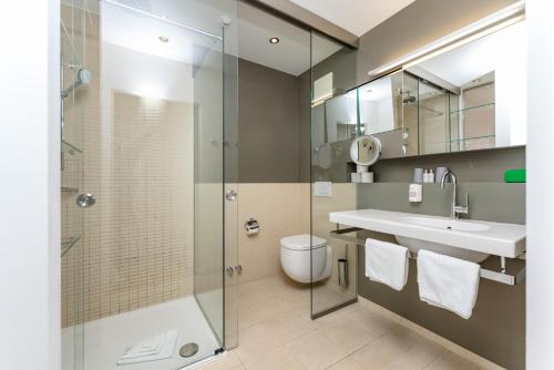 a bathroom with a shower and a sink and a toilet at Hotel Ramsauhof Pool & Wellness Breakfast & Light Dinner Buffet in Ramsau am Dachstein