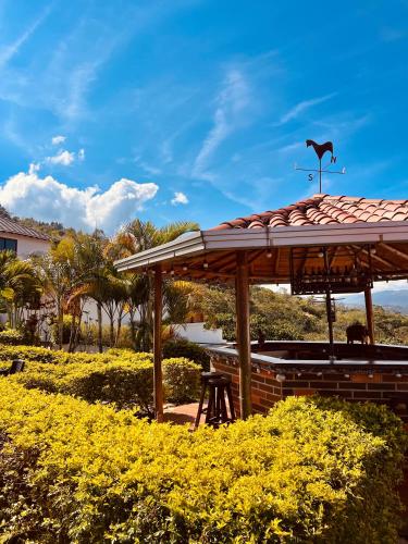 a pavilion with a roof in a field of yellow flowers at Hotel Campestre Palmas del Zamorano in San Gil