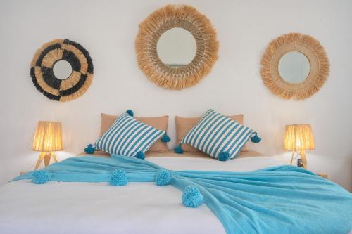 a bed with blue sheets and two mirrors on the wall at La Fattoria Ecolodge in Lalla Takerkoust