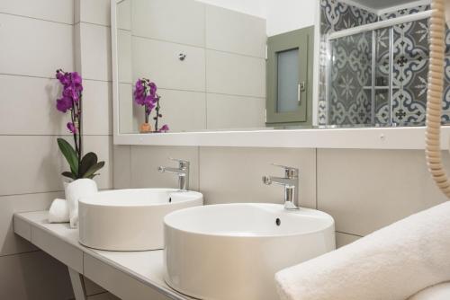 2 umywalki w białej łazience z fioletowymi kwiatami w obiekcie V Hotel Delphi w mieście Delfy