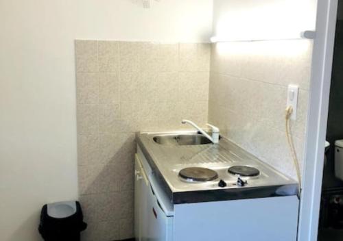 eine kleine Küche mit einem Waschbecken in einem Zimmer in der Unterkunft Studio à 20 min de Walibi in Le Pont-de-Beauvoisin