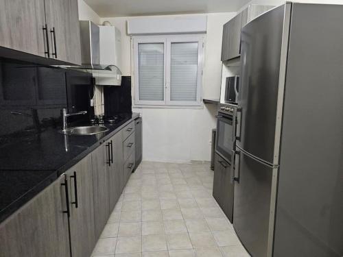 una cucina con frigorifero in acciaio inossidabile e lavandino di Magnifique appartement au bord de la Seine avec parking a Villeneuve-la-Garenne