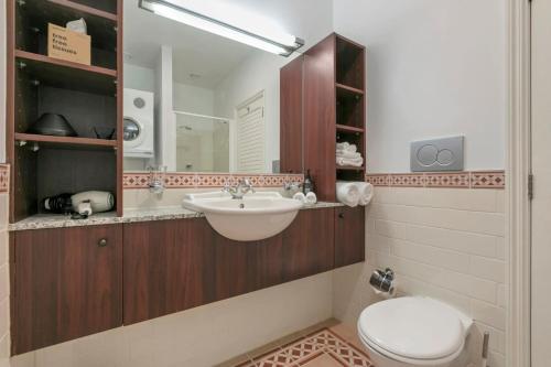 een badkamer met een wastafel, een toilet en een spiegel bij AWSA Deluxe Waterfront (4004) in Auckland