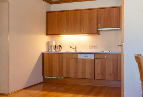 a kitchen with wooden cabinets and a sink at Hotel Ramsauhof Pool & Wellness Breakfast & Light Dinner Buffet in Ramsau am Dachstein