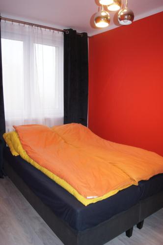a bed in a room with a red wall at Mieszkanie osiedle Północ Zameldowanie 24h in Koszalin
