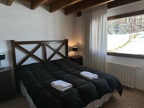 een slaapkamer met een groot bed en 2 handdoeken bij alojamiento en Bariloche CIPRES in Bariloche