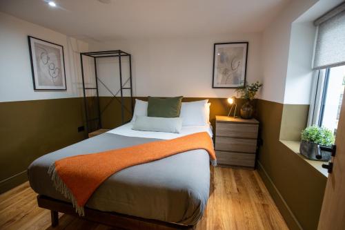 1 dormitorio con 1 cama con manta naranja en RWST Holiday Lodges, en Llanrwst