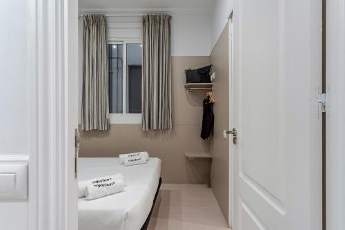 バルセロナにあるEnjoybcn Tapies Apartmentのベッド2台と窓が備わる小さな客室です。