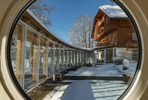 a view of a house in the snow through a window at Hotel Ramsauhof Pool & Wellness Breakfast & Light Dinner Buffet in Ramsau am Dachstein