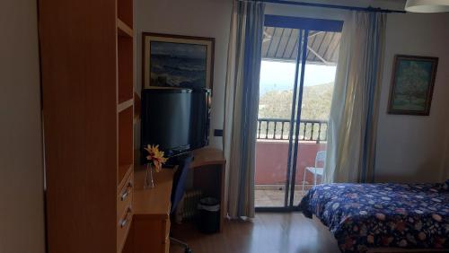 1 dormitorio con TV, 1 cama y balcón en Chalet Anagato en Tegueste