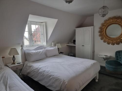 a bedroom with a white bed and a mirror at Poppy Cottage in Whitby