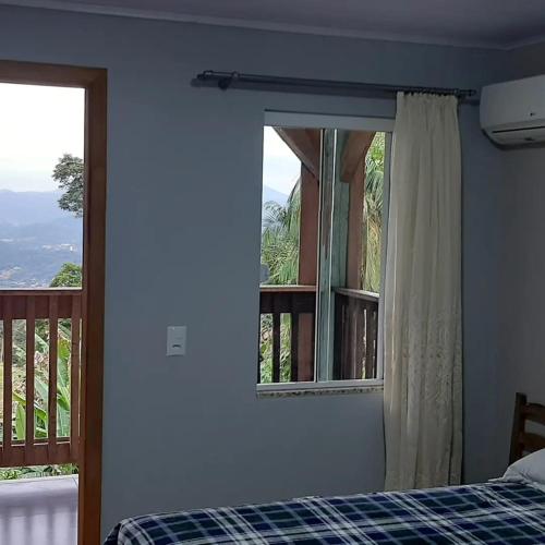 a bedroom with a bed and a window with a balcony at Sitio Hoffmann in Pomerode