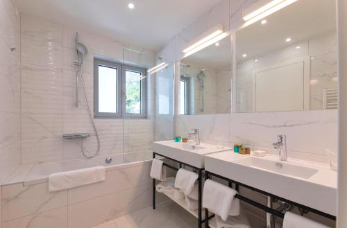 a white bathroom with two sinks and a shower at Hotel Saint Hildegard in Omiš
