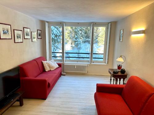 salon z czerwonymi meblami i dużym oknem w obiekcie Monolocale Cristallo 20 - Serafini w Madonna di Campiglio