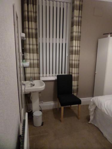 a bathroom with a sink and a chair next to a window at Nathans Guest House in Blackpool