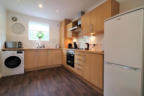 cocina con armarios de madera y nevera blanca en Signature - Belvidere House en Glasgow