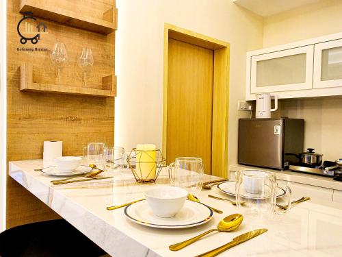 a kitchen with a table with plates and glasses on it at 1 min to Seaview & Sunrise Heart of Kuantan in Kuantan