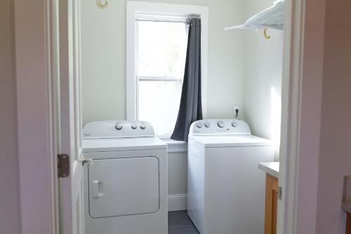 a laundry room with two washers and a window at Beautiful Historic Downtown Pensacola Charmer - Hot Tub in Pensacola
