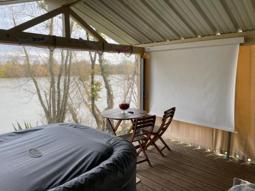 une véranda avec une table et un écran blanc dans l'établissement Chalet cosy bord de Seine 30min paris, à Carrières-sous-Poissy