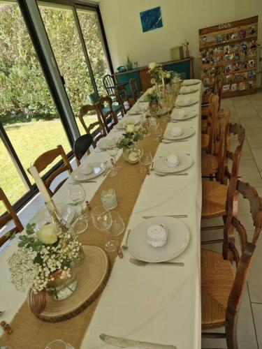 a long table with white plates and flowers on it at Magnifique Maison de Campagne in Saint-Hellier