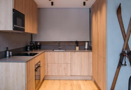 a kitchen with wooden cabinets and a sink at ISARD RESIDENCES & SPA by Vip Residences in El Tarter