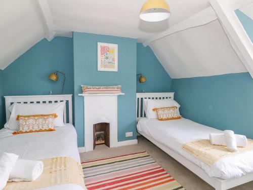 two beds in a room with blue walls at Alice's Cottage in Bridport
