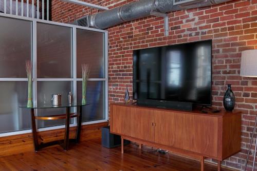 a living room with a flat screen tv on a brick wall at Premier Downtown Loft Building, Just Opened in Pensacola