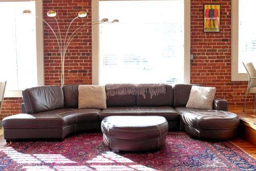 a brown leather couch in a room with a brick wall at Premier Downtown Loft Building, Just Opened in Pensacola