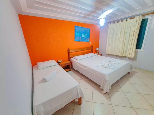1 dormitorio con 2 camas y pared de color naranja en Pousada Praia Bella, en Búzios