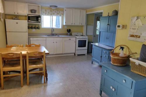 une cuisine avec des placards bleus et une table en bois dans l'établissement Pet Friendly Cottage, à Thompsonville