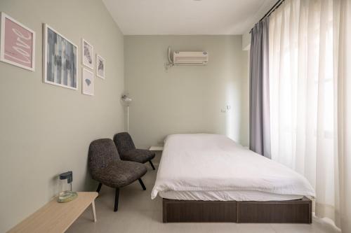 a bedroom with a bed and a chair and a window at Cats in summer in Hengchun