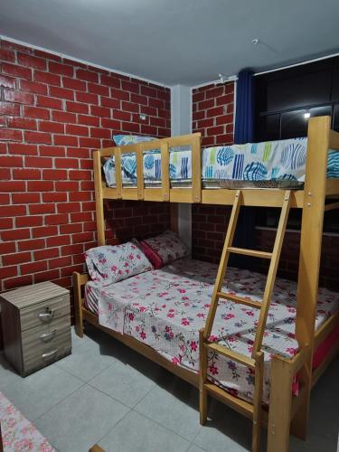 瓦拉爾的住宿－Disfruta de paz y armonía en huaral，砖墙旁边的房间里设有两张双层床