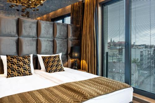 a bedroom with a large bed and a large window at Art Suites Luxury Hotel in Kraków