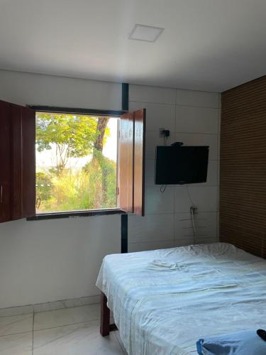 1 dormitorio con 1 cama y ventana con TV en Espaço Diniz, en Santa Luzia