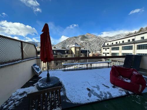 a balcony with a red umbrella and snow on the ground at appartement Terrasse 1 chambre ORDINO HUT3-008298 in Ordino
