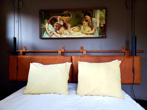 1 cama con 2 almohadas y una pintura en la pared en LOFT - Powered by LIEU -, en Villedaigne