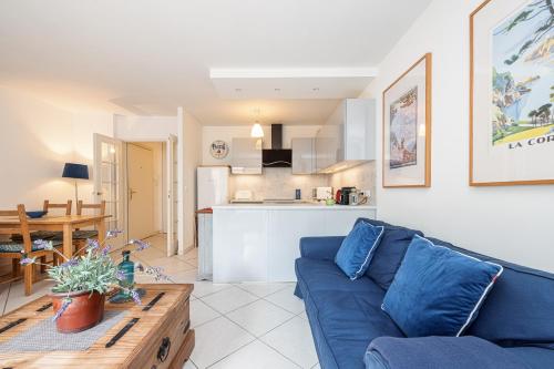 un salon avec un canapé bleu et une cuisine dans l'établissement NEW 2 bed apt in Antibes, 5 min walk to the Beach, à Antibes