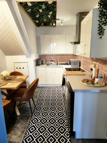 a kitchen with white cabinets and a table and a sink at Home to home studio flat - only 6 minutes to centre - perfect for contractors working in and around Nottingham in Nottingham