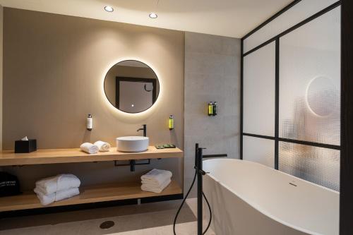 a bathroom with a tub and a sink and a mirror at Sercotel EsteOeste in Lugo