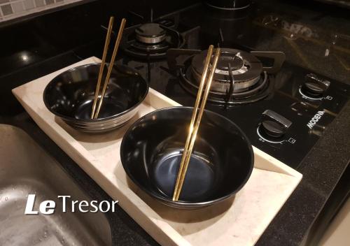 two black bowls sitting on a stove with chopsticks at Le Tresor Benson Apartment at Supermal Pakuwon in Surabaya