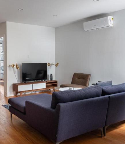 Splendid 2 Bedroom apartment in NYC! في نيويورك: غرفة معيشة مع أريكة زرقاء وتلفزيون