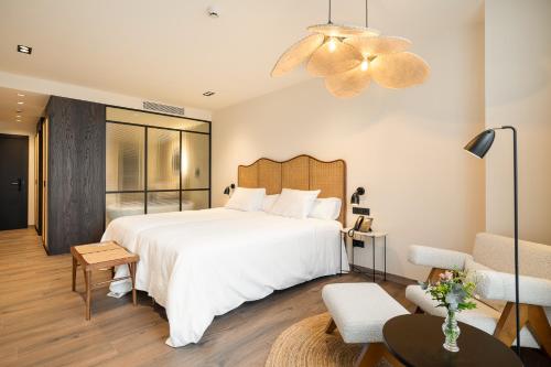 a bedroom with a large white bed and a living room at Sercotel EsteOeste in Lugo