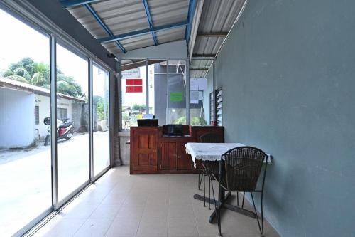a room with a table and chairs in a room with windows at Langkawi Tok Jah Guest House Pantai Cenang in Pantai Cenang