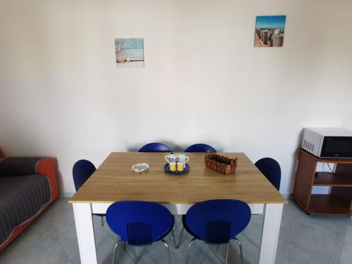 a dining room with a wooden table and blue chairs at Villetta Borgo Pescatori in Torre Pali 