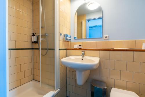 y baño con lavabo, ducha y espejo. en Hotel Omega, en Ámsterdam