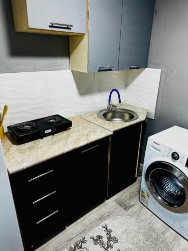 uma cozinha com um lavatório e uma máquina de lavar roupa em Независимости 5а em Sätbaev