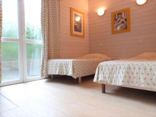 Cette chambre comprend deux lits et une grande fenêtre. dans l'établissement GASMED40 - Golfe de St-Tropez - Chalet californien pour 6 personnes situé dans un parc arboré à Gassin, à Gassin