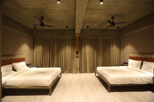 a bedroom with two beds and two ceiling fans at BEL VISTO in Vālpārai